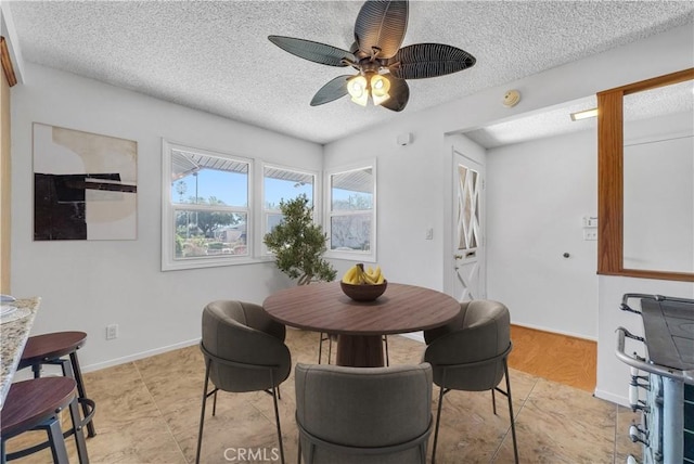 dining area with a textured ceiling, baseboards, and a ceiling fan