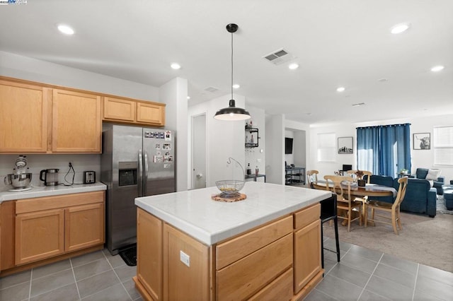 kitchen with pendant lighting, light tile patterned floors, stainless steel fridge, and a kitchen island