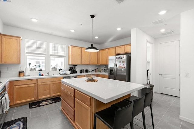 kitchen featuring a kitchen island, sink, hanging light fixtures, light tile patterned floors, and stainless steel fridge with ice dispenser