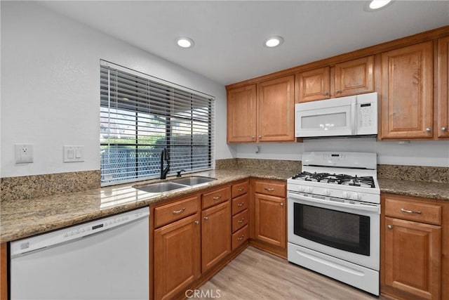 kitchen with light stone counters, white appliances, sink, and light wood-type flooring