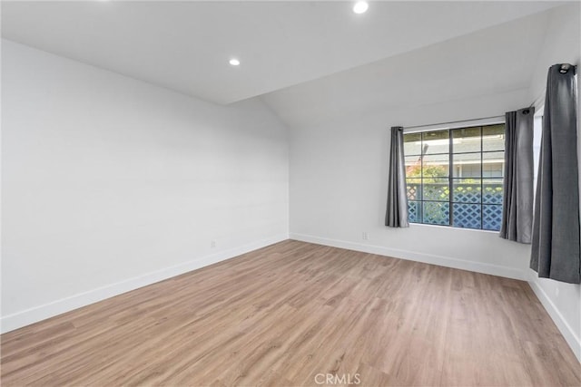 spare room featuring lofted ceiling and light wood-type flooring