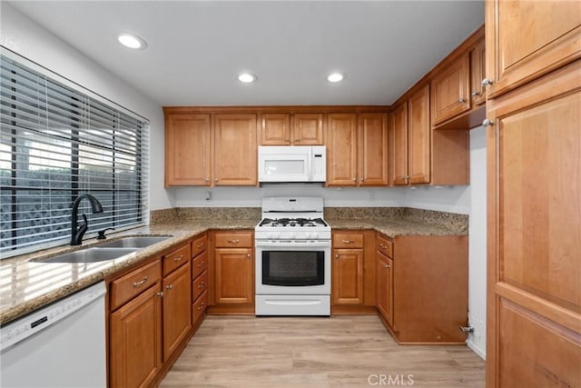 kitchen with light stone countertops, sink, white appliances, and light hardwood / wood-style flooring