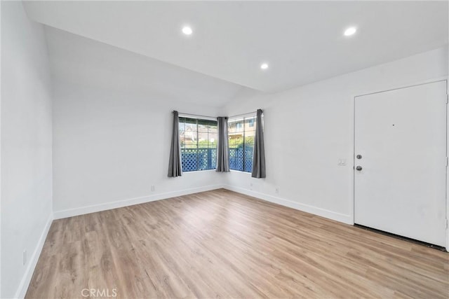 empty room featuring vaulted ceiling and light hardwood / wood-style flooring