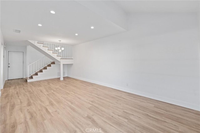 unfurnished living room with a notable chandelier and light hardwood / wood-style floors