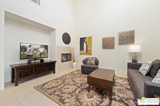 tiled living room featuring a fireplace and a high ceiling