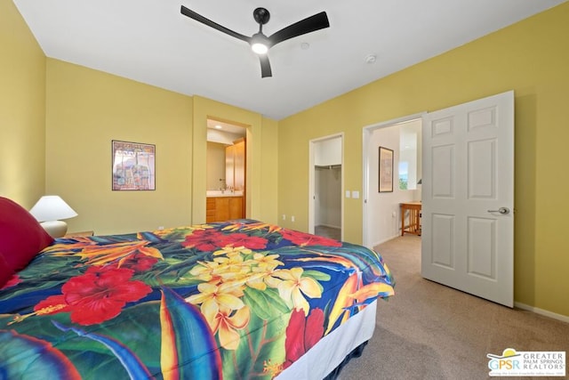 carpeted bedroom with ensuite bathroom, a spacious closet, ceiling fan, and a closet