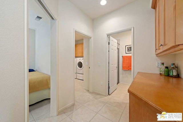 corridor featuring light tile patterned flooring and washer / dryer