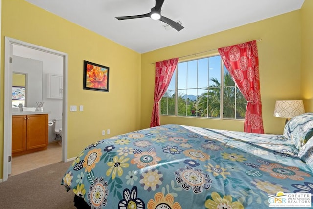 carpeted bedroom with ceiling fan, ensuite bathroom, and sink