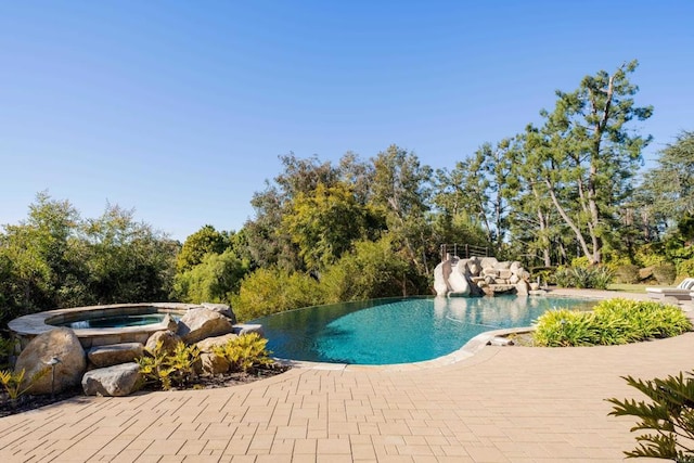 view of pool with a patio area and an in ground hot tub