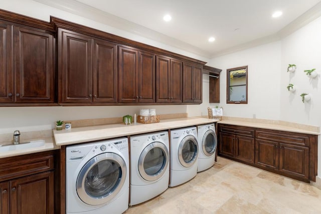 clothes washing area featuring crown molding, cabinets, sink, and washing machine and dryer