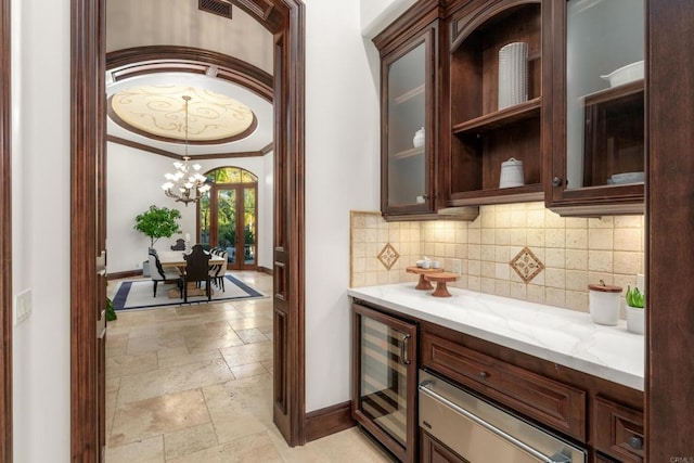 bar featuring crown molding, light stone countertops, wine cooler, and dark brown cabinetry