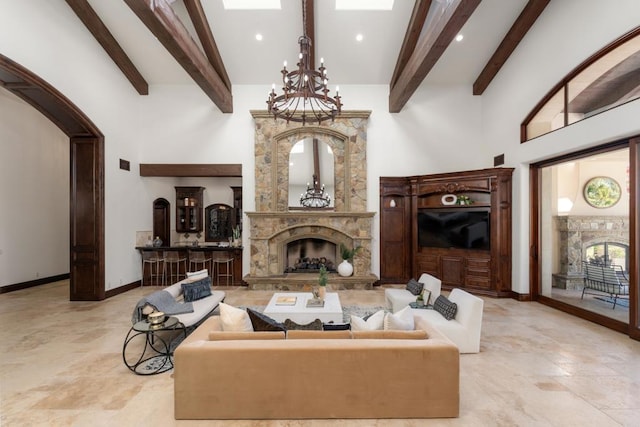 living room with beam ceiling, a fireplace, a chandelier, and a high ceiling