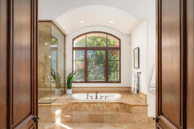 bathroom with tiled tub and vaulted ceiling