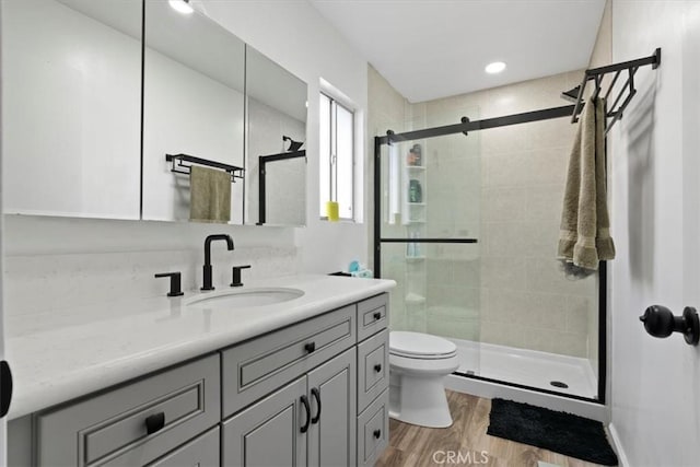 bathroom with vanity, a shower with shower door, wood-type flooring, and toilet