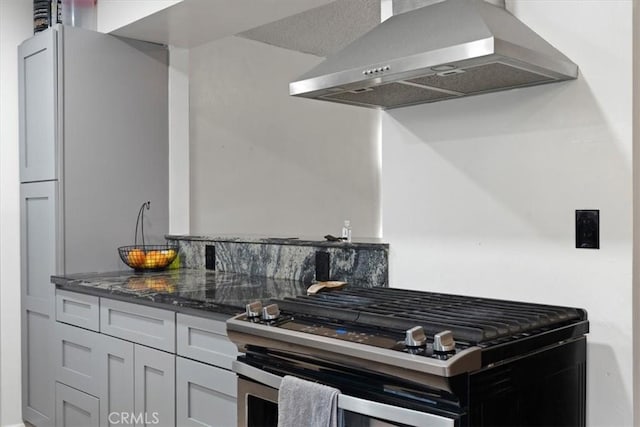 kitchen with extractor fan, gas range, and dark stone counters