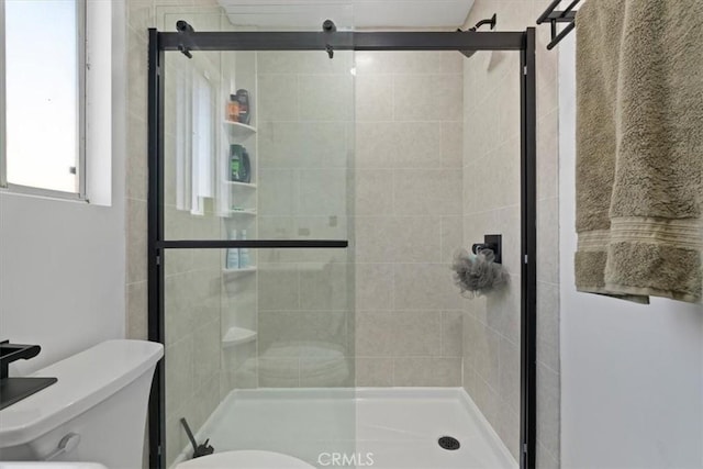 bathroom with toilet and a shower with shower door