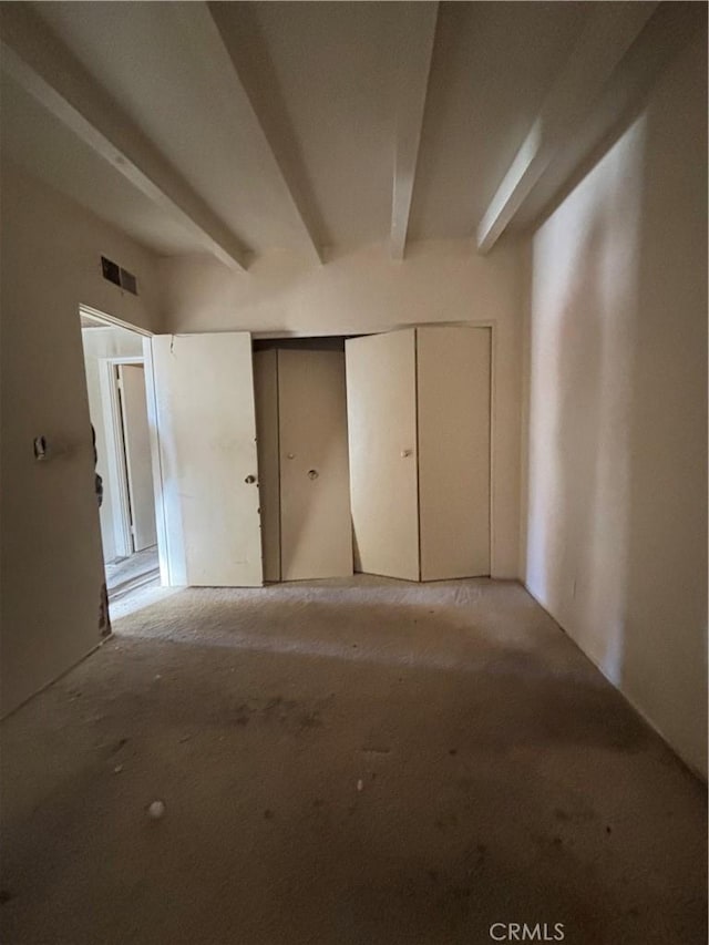 unfurnished bedroom with beam ceiling and a closet