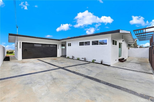 view of front facade featuring a garage, driveway, fence, and stucco siding