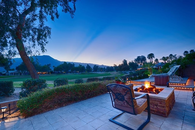 patio terrace at dusk featuring an outdoor fire pit and a mountain view