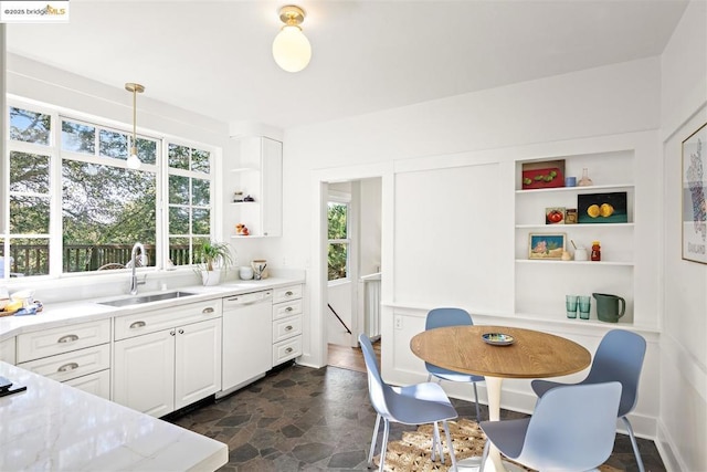 kitchen with sink, white cabinetry, decorative light fixtures, dishwasher, and light stone countertops