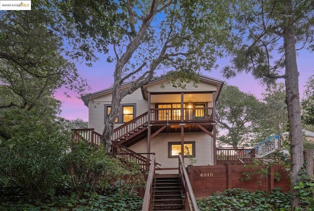 back house at dusk featuring a wooden deck