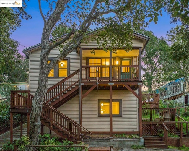 back house at dusk featuring a wooden deck