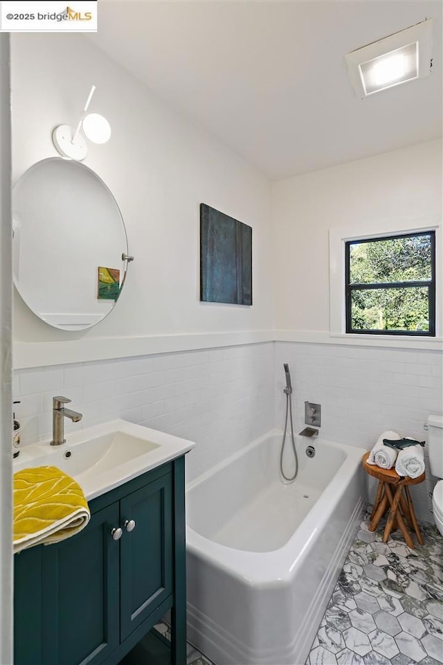 bathroom featuring vanity, a bathtub, tile walls, and toilet