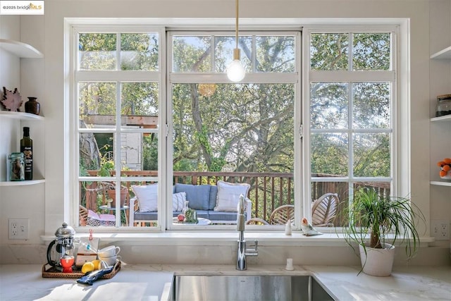 interior space featuring hanging light fixtures, light stone countertops, and sink