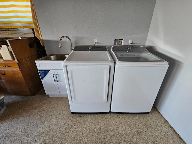 clothes washing area featuring cabinets, washing machine and clothes dryer, and sink