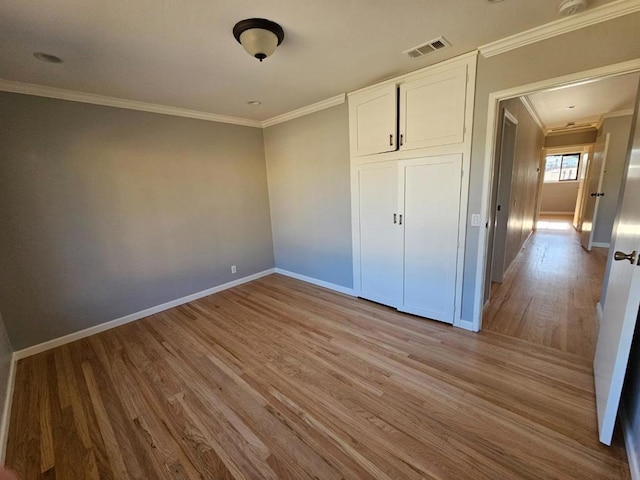 unfurnished bedroom featuring ornamental molding, a closet, and light wood-type flooring