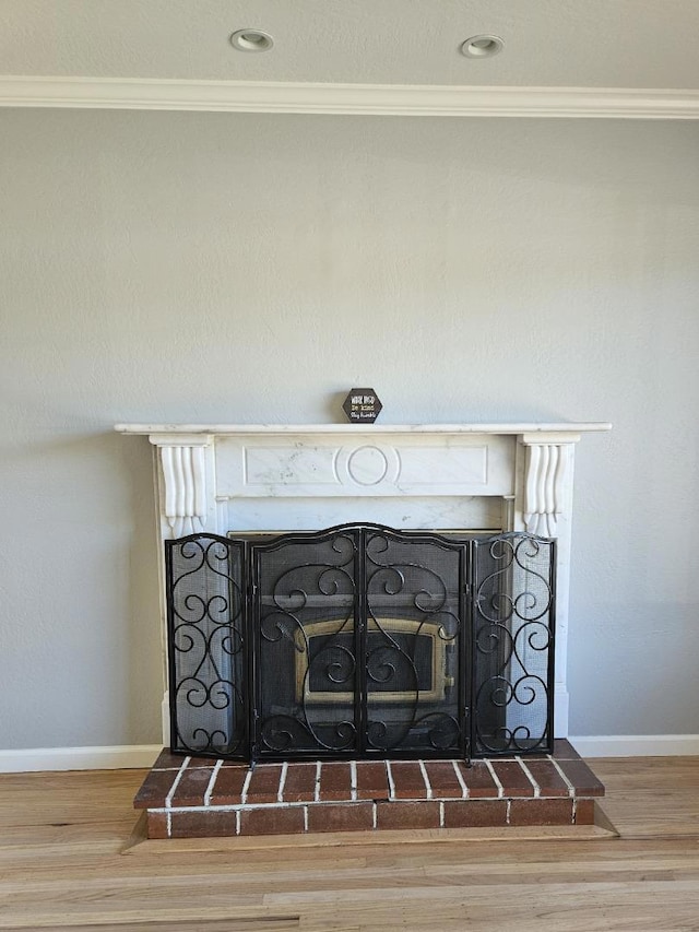 interior details with a brick fireplace, wood-type flooring, and ornamental molding