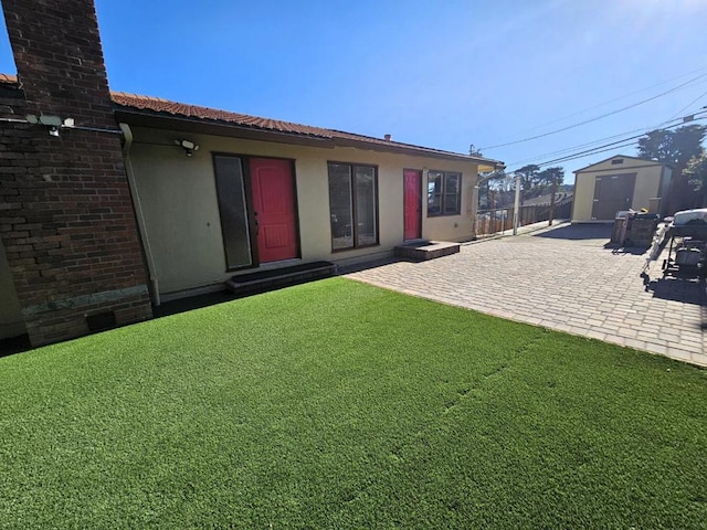 rear view of house featuring a storage unit, a lawn, and a patio area