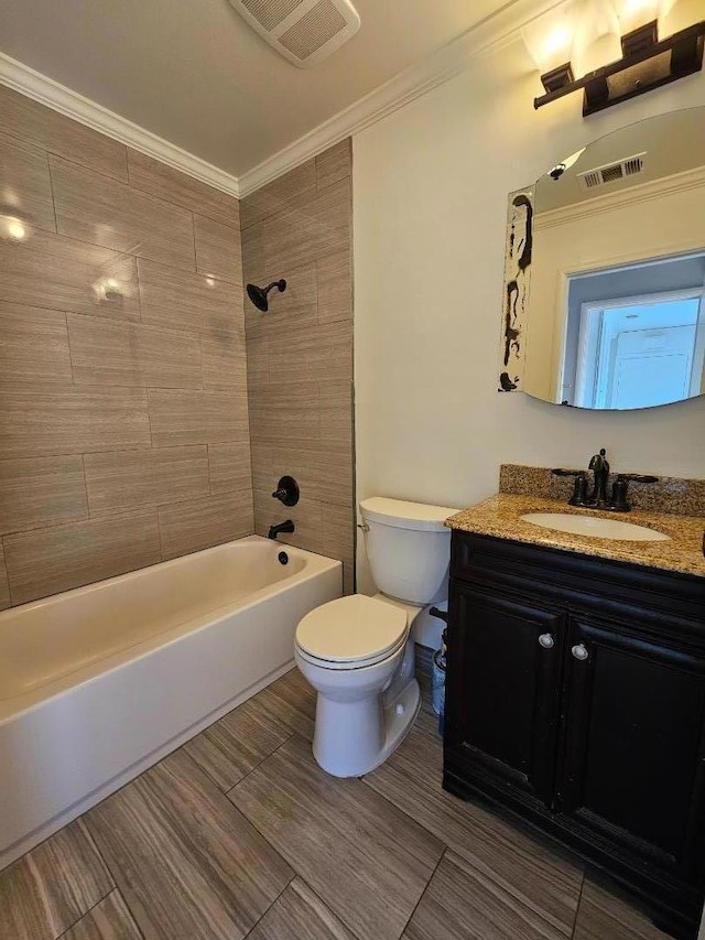 full bathroom with tiled shower / bath, vanity, crown molding, and toilet