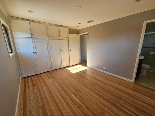 unfurnished bedroom with ensuite bathroom, ornamental molding, and light wood-type flooring