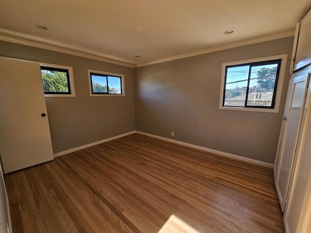 unfurnished room featuring crown molding, wood-type flooring, and plenty of natural light