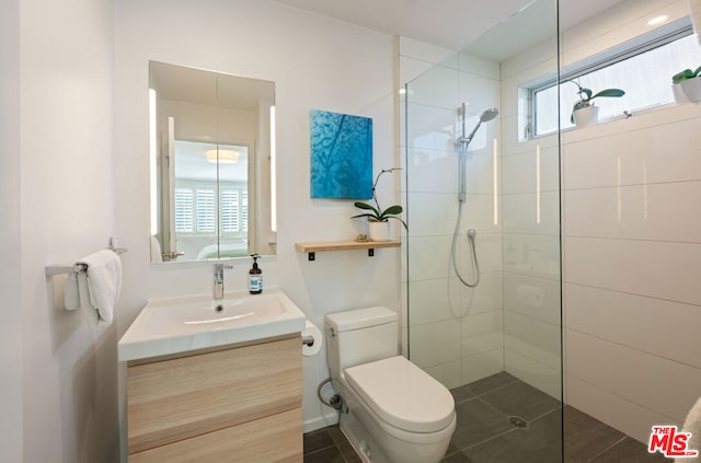 bathroom featuring vanity, toilet, and a tile shower