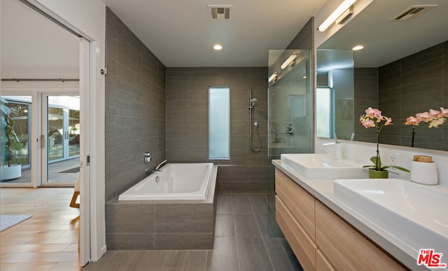 bathroom featuring vanity, tile patterned flooring, independent shower and bath, and tile walls