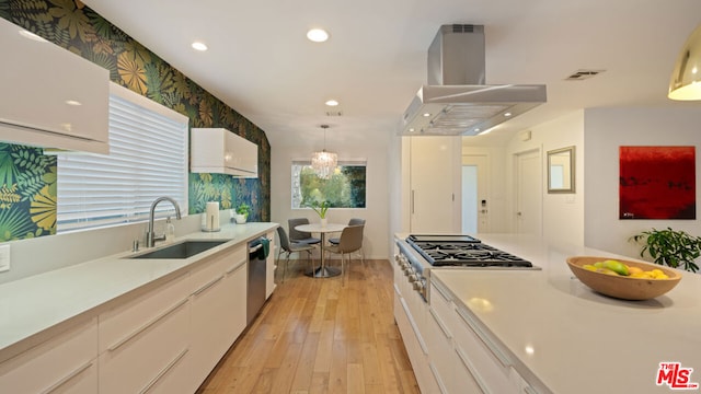 kitchen with island range hood, decorative light fixtures, sink, white cabinets, and light hardwood / wood-style flooring