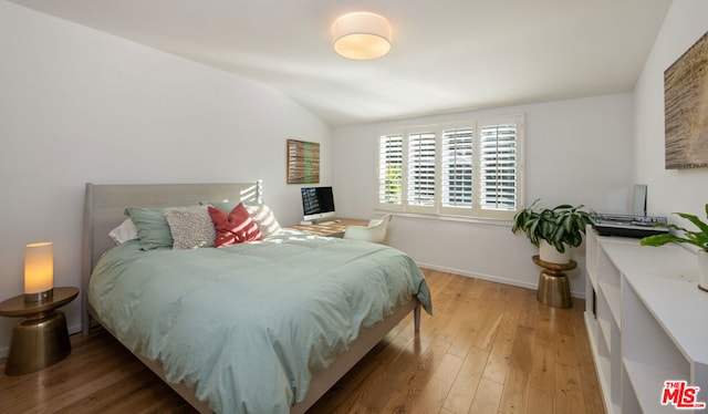 bedroom with wood-type flooring and vaulted ceiling