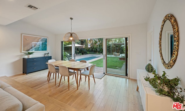 dining area featuring vaulted ceiling and light wood-type flooring