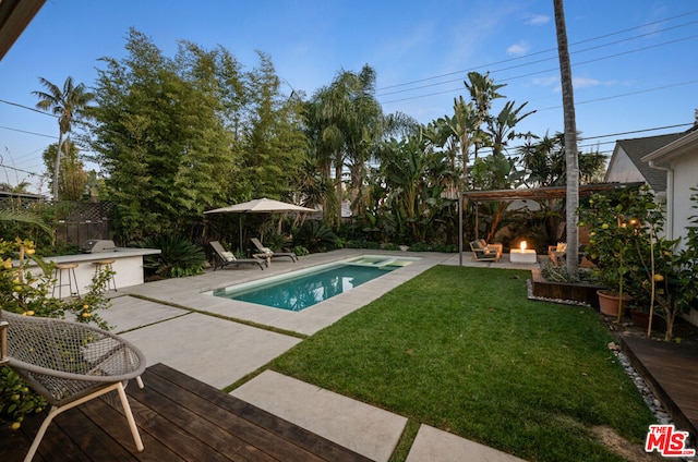 view of pool featuring a yard, a patio, an outdoor bar, and exterior kitchen