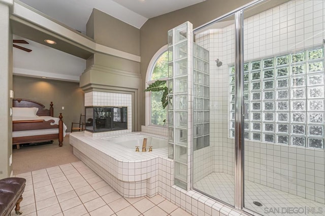 bathroom featuring vaulted ceiling, independent shower and bath, a tiled fireplace, ceiling fan, and tile patterned floors