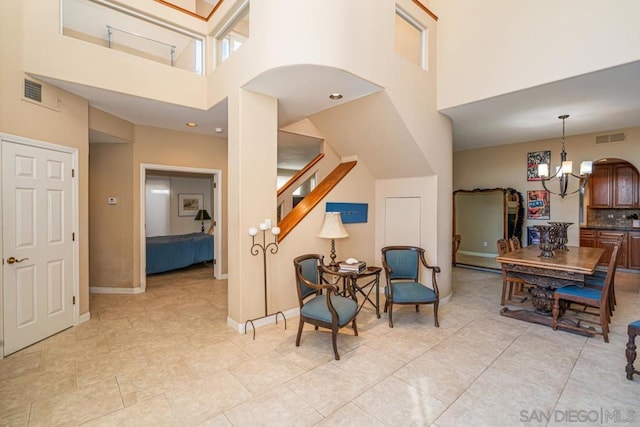 living area featuring an inviting chandelier, a towering ceiling, and light tile patterned flooring