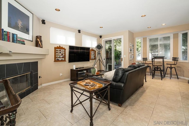 living room featuring a tiled fireplace and light tile patterned floors