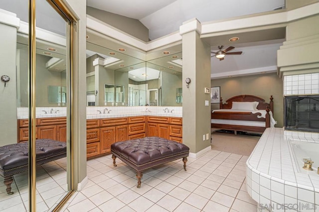 bathroom with tile patterned floors, lofted ceiling, vanity, a relaxing tiled tub, and ceiling fan