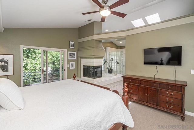 carpeted bedroom with lofted ceiling, access to exterior, a tile fireplace, and ceiling fan