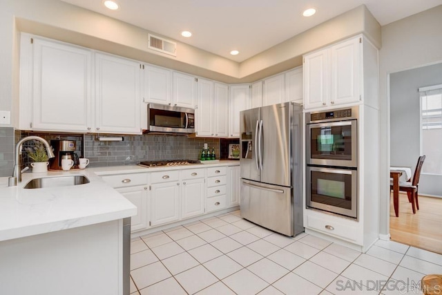 kitchen featuring white cabinetry, stainless steel appliances, light tile patterned flooring, and sink