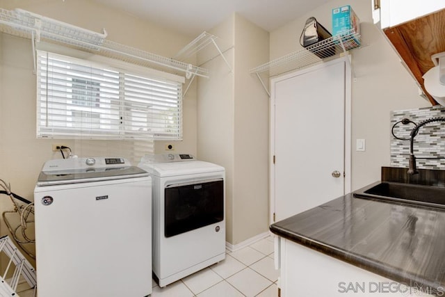 washroom featuring light tile patterned floors, sink, and washing machine and clothes dryer