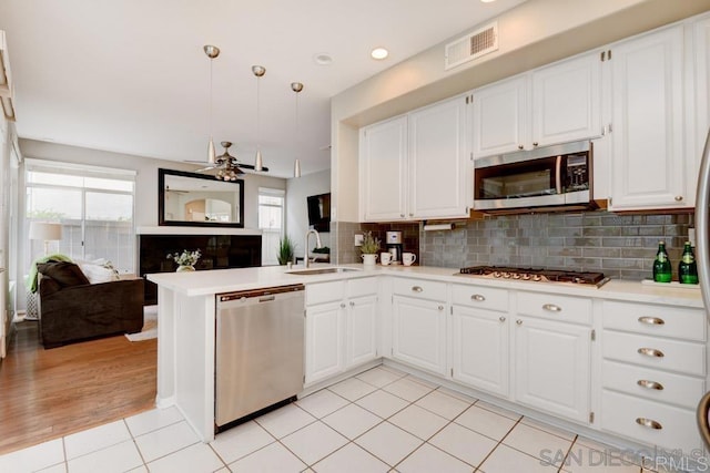 kitchen with stainless steel appliances, kitchen peninsula, sink, and white cabinets