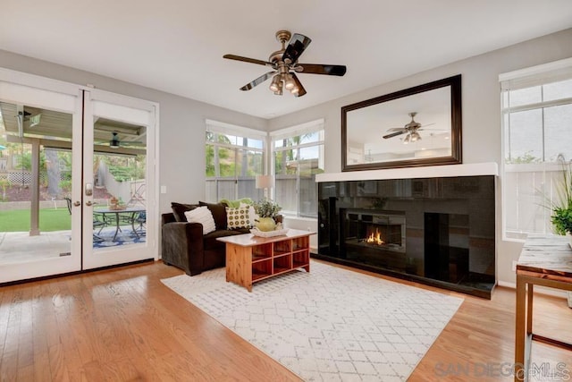 living room featuring hardwood / wood-style flooring, ceiling fan, and a tiled fireplace